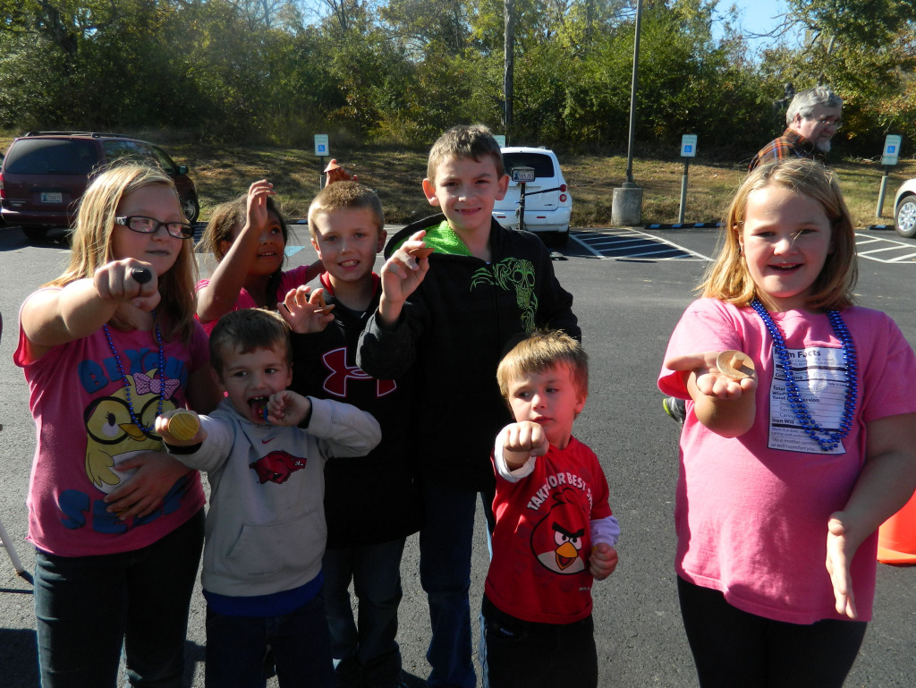 Kids proudly showing off wooden toy tops from the woodturners